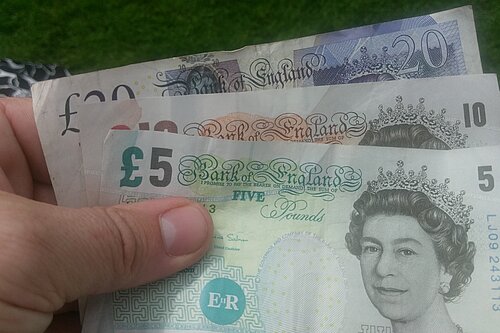 Three bank notes (UK money - £5, £10, £20) in hand 